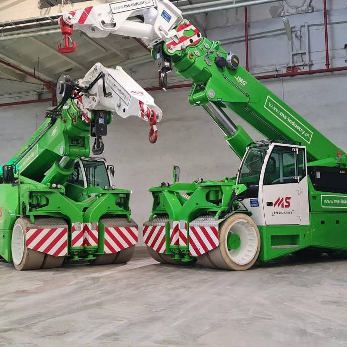 Dwa elektryczne żurawie JMG w hali przemysłowej, przygotowane do realizacji prac transportowych. 