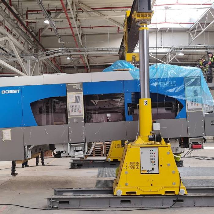 Instalacja maszyny BOBST Mastercut przy użyciu hydraulicznego systemu podnoszenia. 