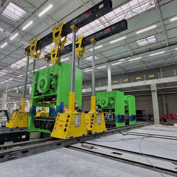 Kontrolowane obracanie korpusu prasy przemyslowej podczas procesu instalacji w hali produkcyjnej. 