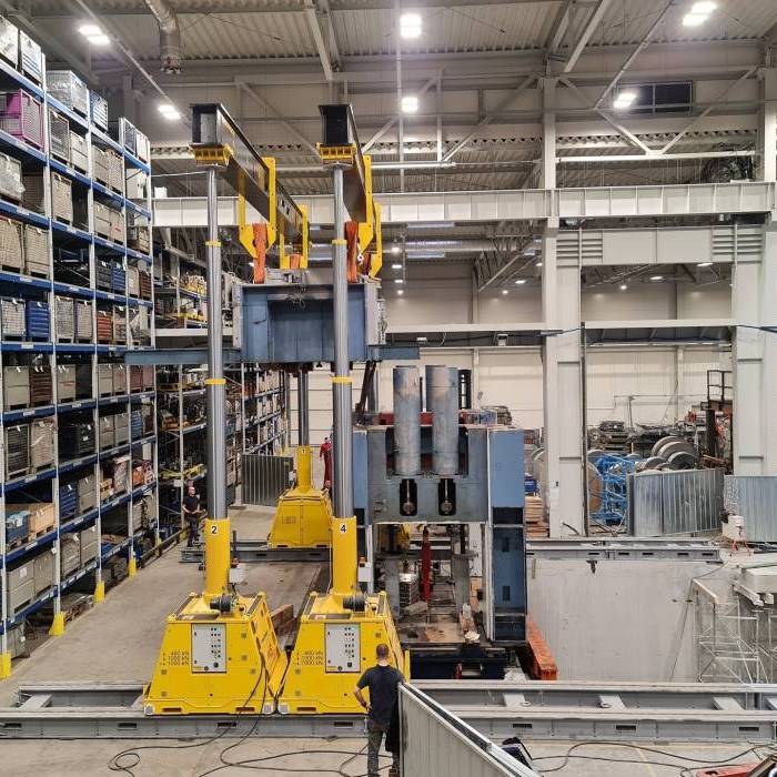 Instalacja maszyny z użyciem czterech kolumn podnoszących Enerpac w hali magazynowej. 